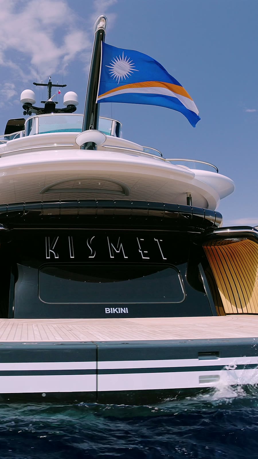 Still from the Kismet reveal film, the yacht's stern and Marshall Islands flag from the water